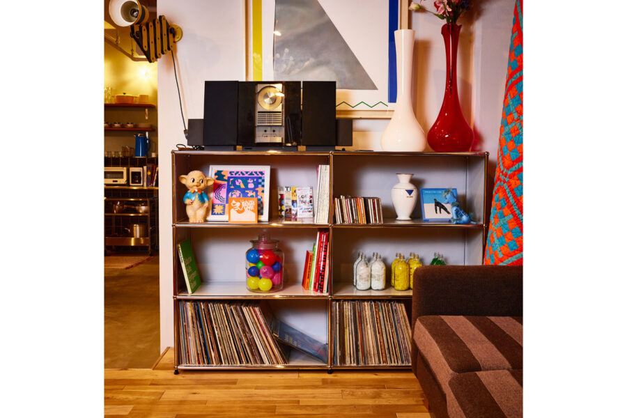 Shelving unit with vinyl records, jars, books, and a vintage stereo in a cozy living room setting.