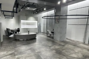 Modern, minimalist showroom with a circular concrete ottoman and white seating area against white walls.