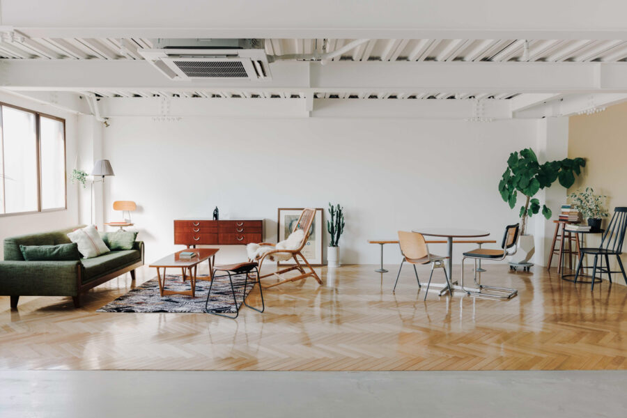 Bright open living area with a green sofa, wooden coffee table, and mid-century chair on a patterned rug.
