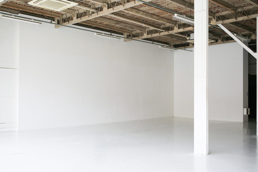 328A5083++ Empty white studio space with a concrete ceiling and a white pillar in the foreground.