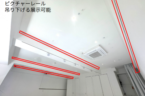 Ceiling-mounted picture rails for hanging displays, highlighted in red outlines with track lighting nearby