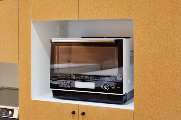 Compact Toshiba countertop oven installed in a wooden cabinet niche in the kitchen, viewed head-on with glass door.