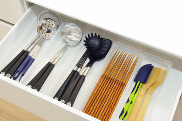 Organized kitchen drawer with ladles, slotted spoon, spaghetti-measuring sticks, and spatulas in separate compartments