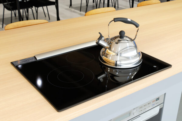 101 Stovetop induction cooktop with a shiny kettle on it in a modern kitchen setting.
