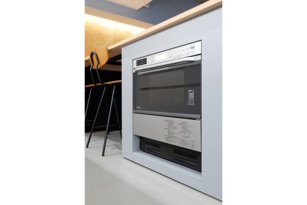 102 Built-in oven in a gray cabinet under a wooden counter, with black bar stools to the side in a modern kitchen.