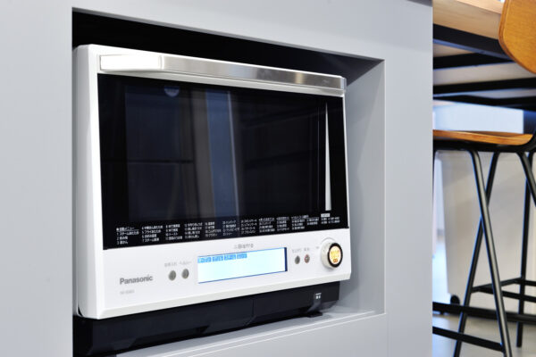 103 Built-in white Panasonic microwave in a recessed gray cabinet with a digital display and control panel at the bottom edge.