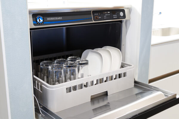 104 Dishwasher with its door open, loaded with glassware and white plates in a rack on the bottom rack