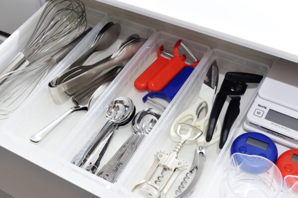 108 Organized kitchen utensil drawer with stainless spoons, forks, a whisk, and other tools separated in clear compartments.