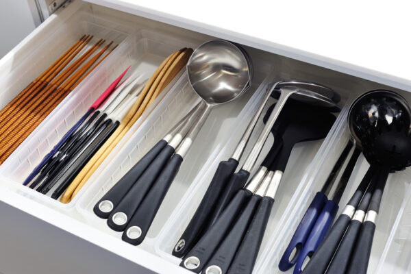 109 Organized kitchen utensil drawer with separate compartments holding skewers, ladles, spatulas, and scissors in a white tray.
