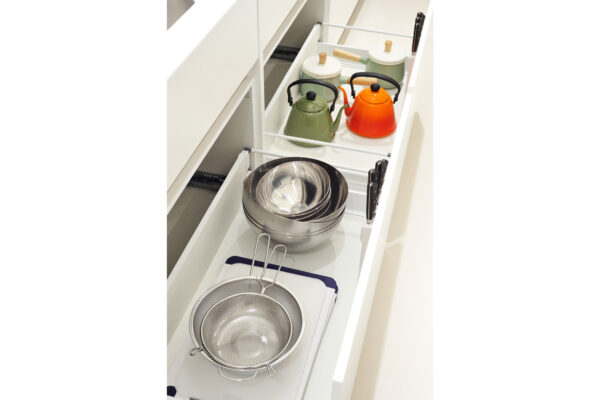 Pull-out kitchen drawer with metal bowls, a metal strainer, and nested utensils for washing and storage.