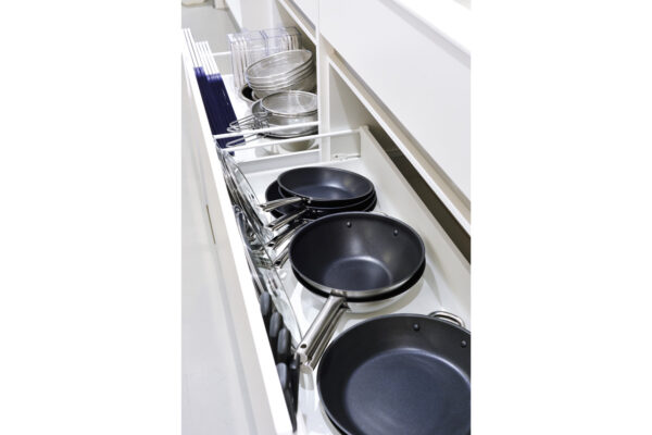 111 Pull-out kitchen drawer filled with frying pans, skillets, and cookware neatly arranged next to utensils and glass lids.