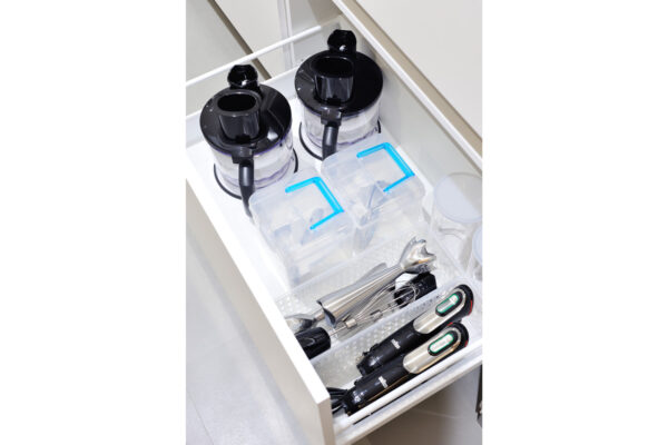 112 Open drawer showing two black blender bases, glass jars, and plastic containers with blue lids for storage in a organized kitchen drawer.
