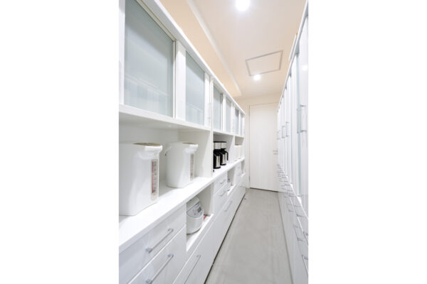 113 Narrow white utility galley with glass-front cabinets and appliances (kettles) along the left, tall drawers on the right.