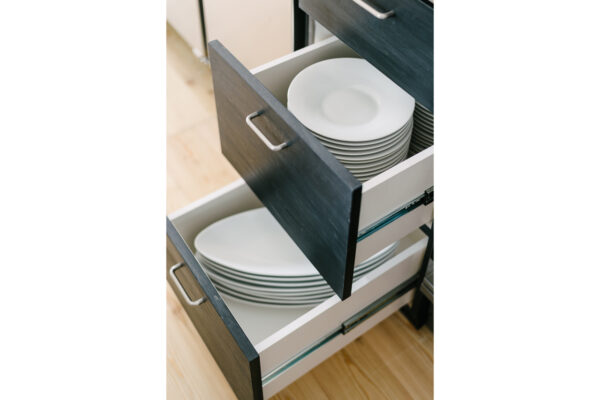 Open kitchen drawer with two stacks of white plates neatly arranged inside the cabinet.