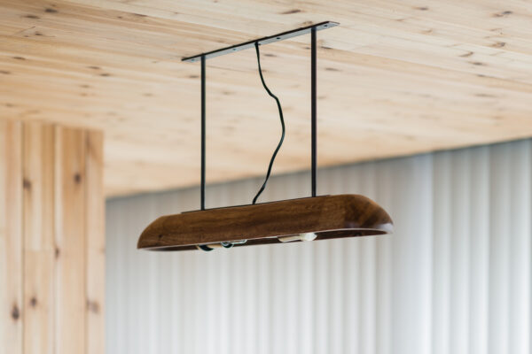 2017_0303_0045 Wooden pendant light fixture suspended from the ceiling by two black rods and a wavy cord