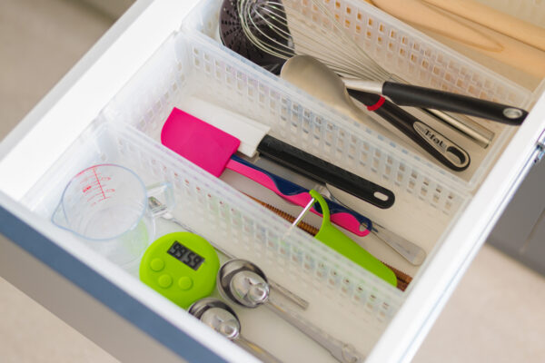 2017_0303_0062 Neatly organized kitchen drawer with utensils in a dividered tray: whisk, spatulas, tongs, and a green digital timer visible nearby.