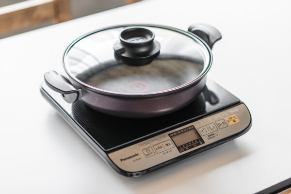2017_0303_0074 Pan sits on a glass-topped induction cooker with a glass lid and black handles, ready to cook on a white countertop.