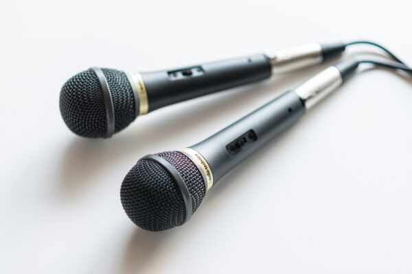 2017_0303_0084 Two black handheld microphones with metal mesh grilles lying on a white surface, close-up.