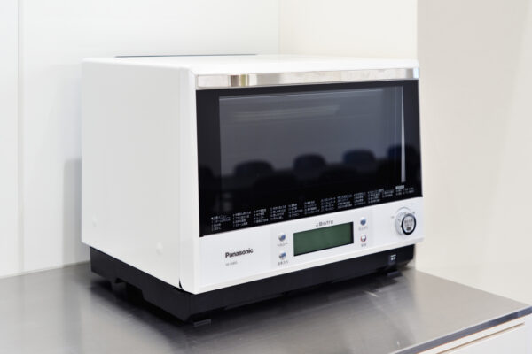 White Panasonic countertop microwave oven on a stainless steel surface.