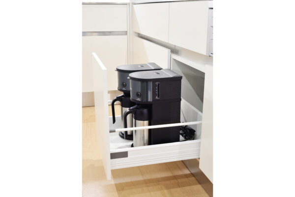 Double espresso machine stored in a pull-out kitchen cabinet under white countertops.