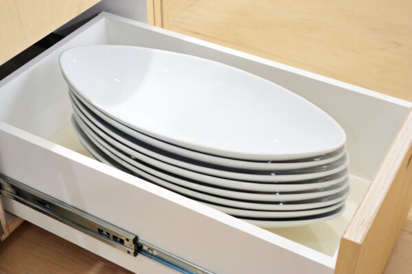 Stack of white ceramic plates inside an open kitchen drawer.