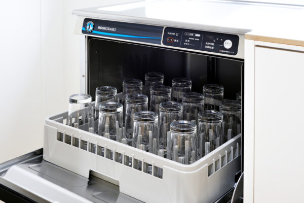 Dishwasher with the door open and glass tumblers stored upright in the rack inside the tub to be washed